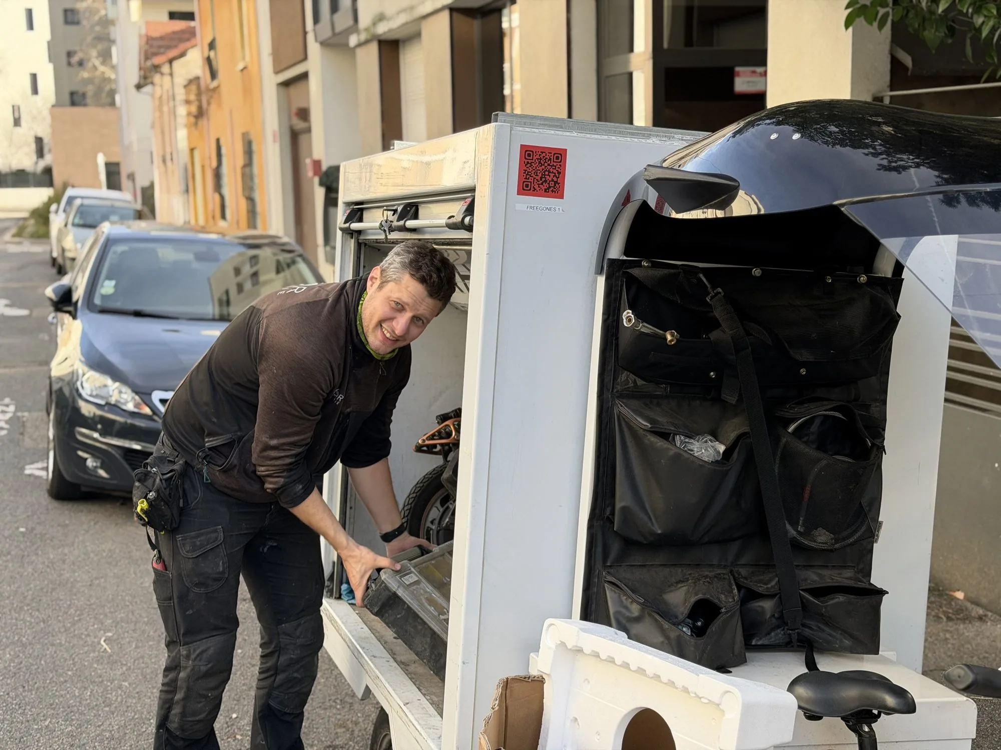 Rémy chargeant le coffre du triporteur dans une rue de Lyon.
